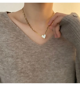 Close-up of heart-shaped pendant necklace with gold chunky chain worn by a model