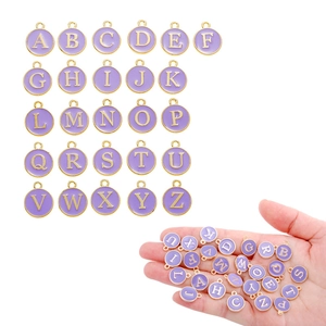 Round purple enamel alphabet charms with gold frame showing scale in hand