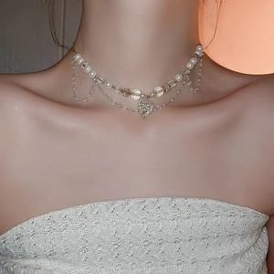 Gros plan du collier coeur avec perles multicouches et strass sur le cou d'une femme