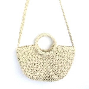 Detail of straw woven bucket bag with circular handle and braided shoulder strap