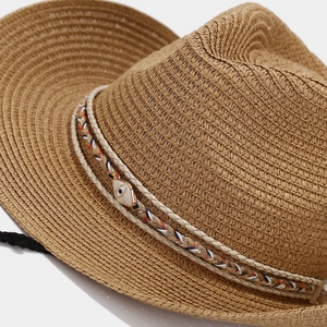 Detail of hand-woven straw hat texture featuring a bohemian evil eye decorative band