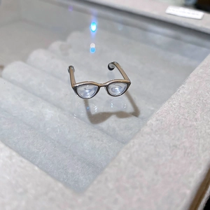 Macro shot of silver y2k eyewear shaped ring with transparent lenses on grey velvet