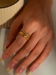 Detail view of wavy gold titanium steel ring on model hand with lifestyle background