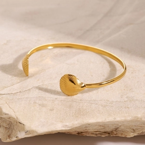 Detailed view of a golden shell open bracelet with textured ocean-themed seashell ends