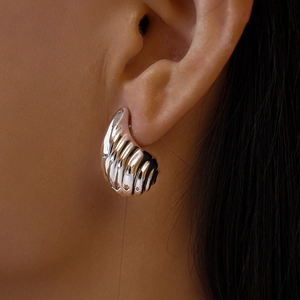 Gros plan de boucles d'oreilles géométriques argentées portées par un mannequin