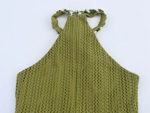 Detail of green knit halter neck dress showing intricate mesh texture and woven trim