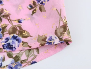 Dettaglio del tessuto boho rosa con stampa floreale blu e motivi in foglia dorata