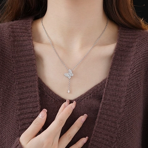 Close-up of a silver butterfly pendant necklace with sparkling zircons worn by a model