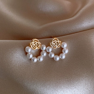 Macro shot of gold floral earrings with pearls on silk, showing intricate rose petal detail