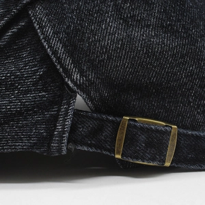 Macro shot of retro bronze adjustable metal buckle and washed black denim fabric