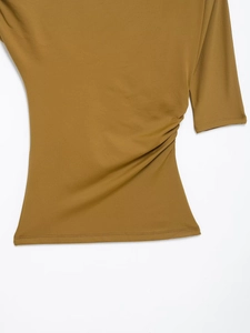 Detailed close-up of mustard yellow knit top with side ruched design and clean stitching