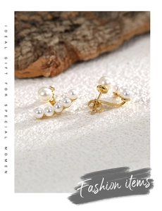 Macro detail of elegant gold curved pearl earrings with five small and one large shell pearls