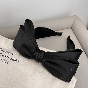 Detailed view of the layered black silk satin bow headband with sparkling crystal accents