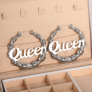 Übergroße silberne Creolen im Bambusstil mit Queen-Schriftzug in einer Schmuckschatulle
