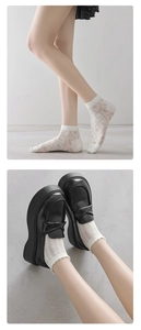 Close-up of white knitted ballet style lace socks with floral diamond patterns and loafers