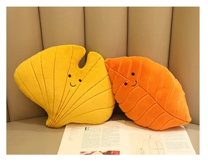 Detail of yellow ginkgo and orange leaf plush pillows with cute embroidered smiling faces