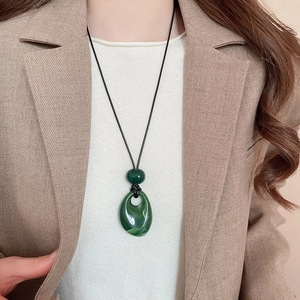 Detail of vintage wax cord necklace with dark green resin teardrop pendant on model