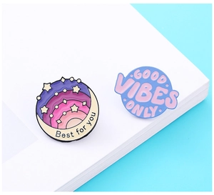Detail of round enamel pins with Good Vibes Only and Best for you text on notebook