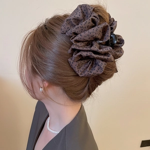 Détail d'une grande pince à cheveux en tissu imprimé léopard portée en chignon élégant