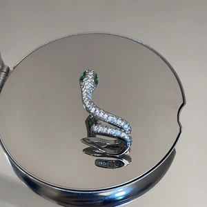 Détail d'une bague serpent en argent avec zircons blancs et yeux en pierre verte