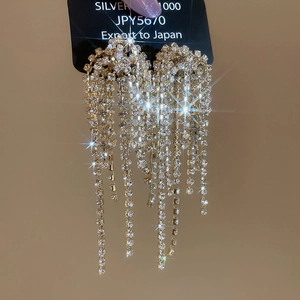 Macro shot of silver tassel earrings with sparkling rhinestones displayed on a black card