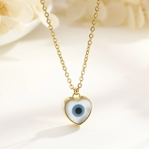 Macro shot of 18k gold plated heart pendant with blue evil eye design and pearl white inlay