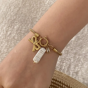 Elegante bracciale dorato con fiocco, perle irregolari e strass sul polso della modella