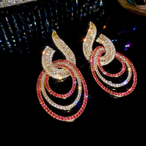 Macro view of gold-plated drop earrings with pavé-set red and white crystals