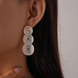 Detail of silver hollow mesh earrings featuring a triple-tiered geometric circle design