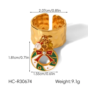 Detail of golden Christmas ring with bell pendant, showing hammered texture and pearl