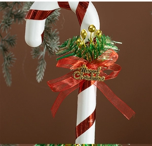 Detail of red and white candy cane ornament with Merry Christmas bow and pine needles