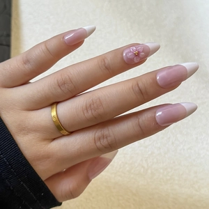 Detailed macro of French almond press-on nails with 3D carved pink flowers and gold beads