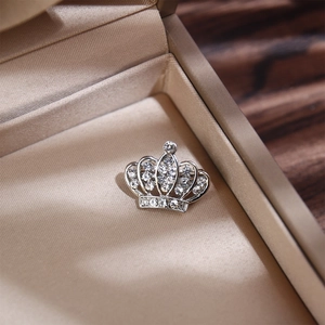 Vue détaillée d'une broche couronne argentée avec strass brillants dans son écrin