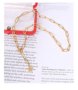 Detail of 18k gold plated paperclip chain necklace with a solid star pendant on art book