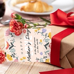Mother's Day card with pink floral design leaning on a gift box next to carnations
