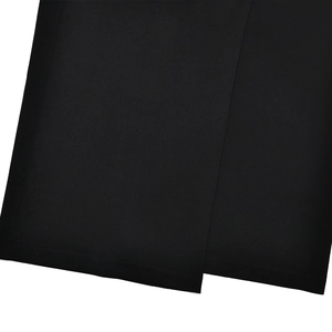 Detail view of high waist trousers showing the slit hem and textured black fabric
