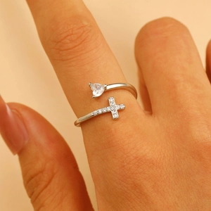 Close-up of silver double cross and heart zircon ring on finger highlighting detailed craft