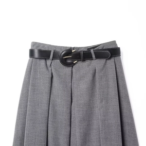 Detailed close-up of high-waist pleated grey skirt with slim black leather belt and gold buckle