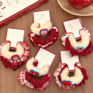 Detail of red plush scrunchies with cute charms on a rustic wooden background