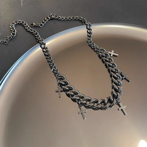 Black Cuban chain necklace with multiple cross pendants on a metallic tray