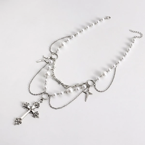 Detail of layered silver necklace with pearls, star charms and gothic cross pendant