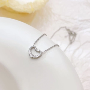 Elegant silver heart necklace with sparkling zircon stones on a white artistic display