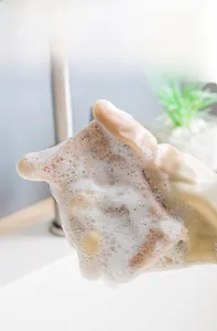 Close-up of natural wood pulp sponge generating rich foam for effective dishwashing