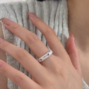 Detail of silver S925 ring with blue zircons and vertical brushed texture on model