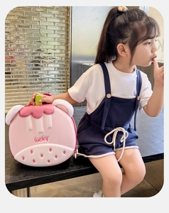 Pink strawberry hard shell toddler backpack with lucky embossment worn by girl