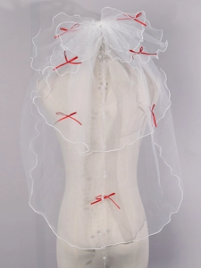 Detailed view of white bridal veil with wavy edges, pearls, and red mini bows