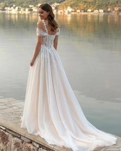Detail of off-shoulder lace straps and layered tulle skirt on a champagne bridal gown