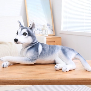Realistic gray and white husky plush toy in a lying position on a wooden table
