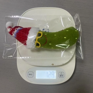 Detailed view of Christmas green banana plush pendant on scale showing 12.9g weight