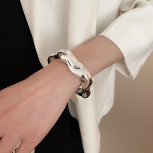 Bracciale rigido argento irregolare a fascia larga indossato con blazer bianco